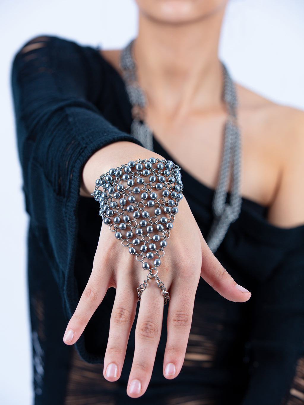 Person wearing a silver beaded hand chain with a blurred background